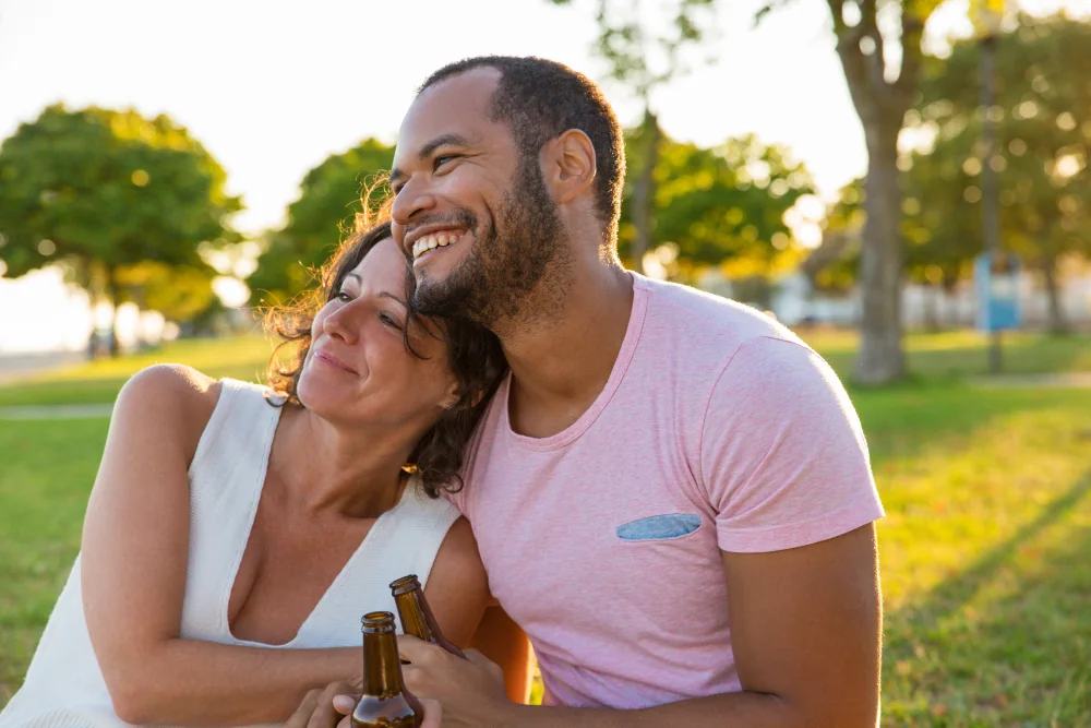 An outdoor couple smiling together in a sunny park