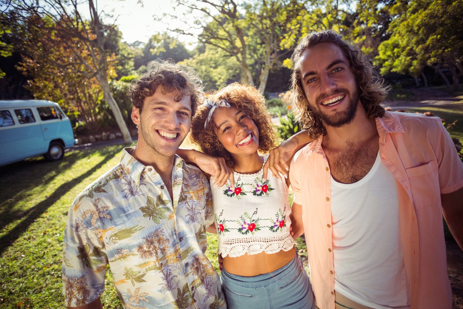 Three friends smiling together in a sunny park