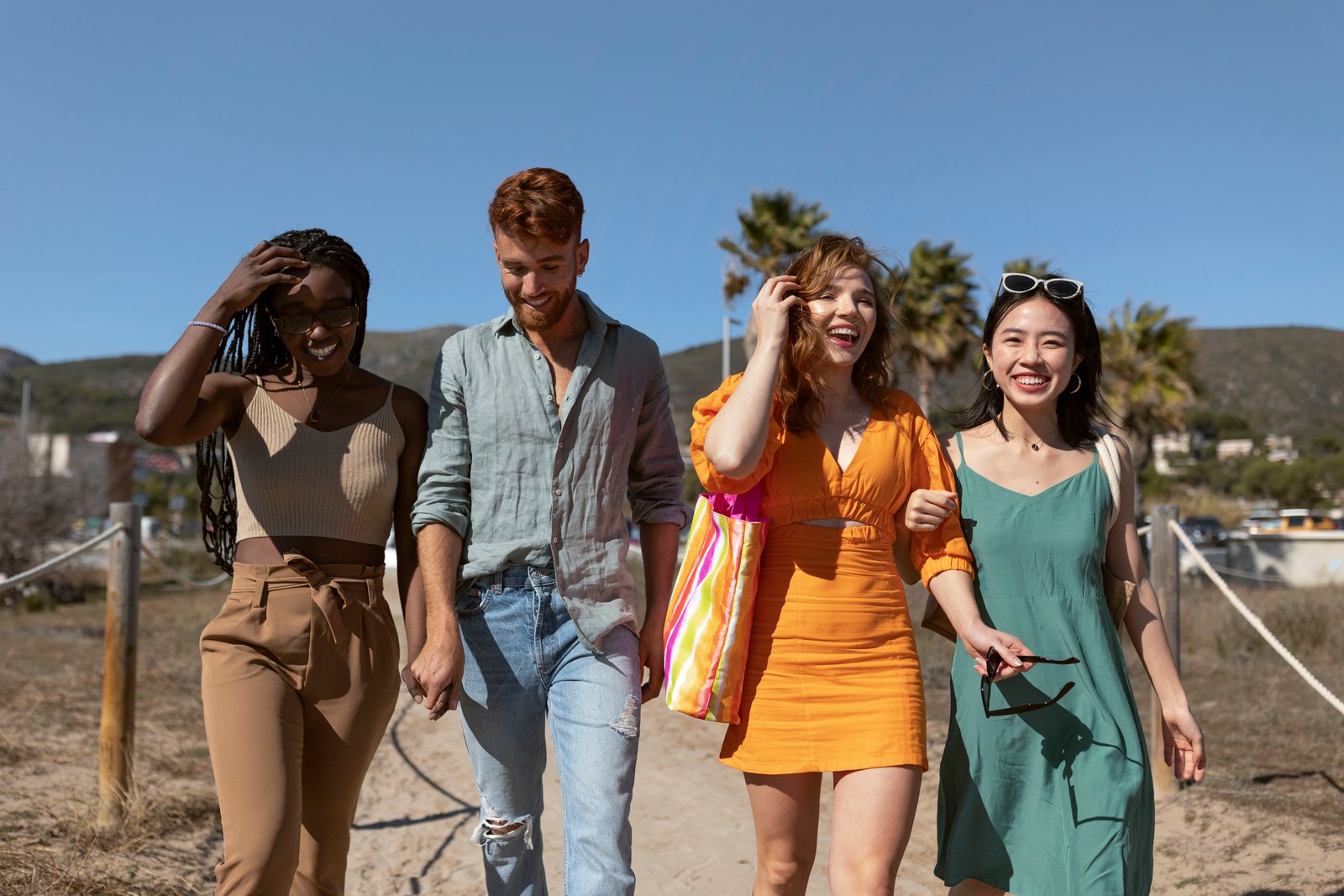 Four friends walking together and smiling on a coastal path